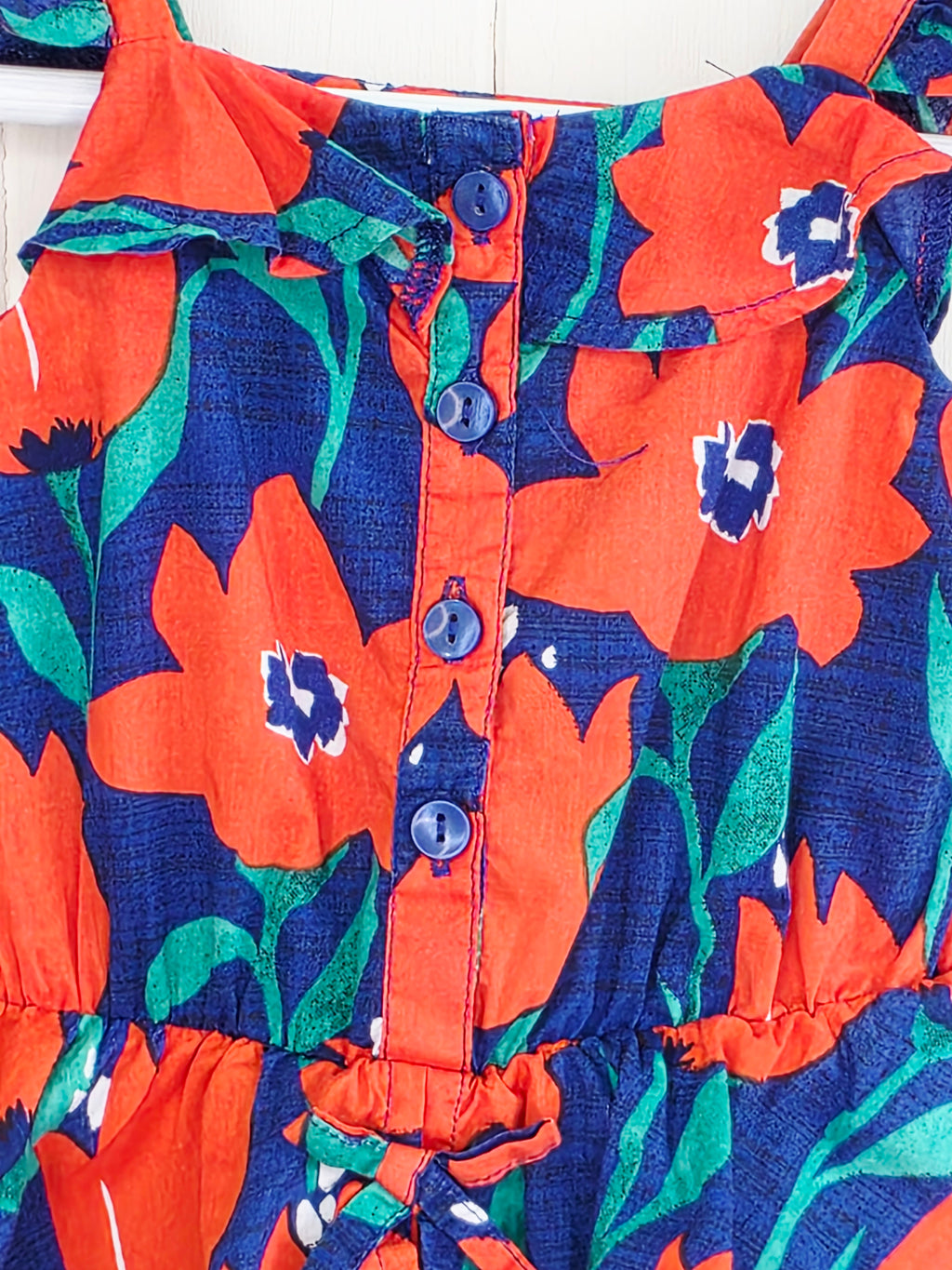 Next 3-6 months floral-print baby romper features a vibrant red and blue color scheme with ruffled straps