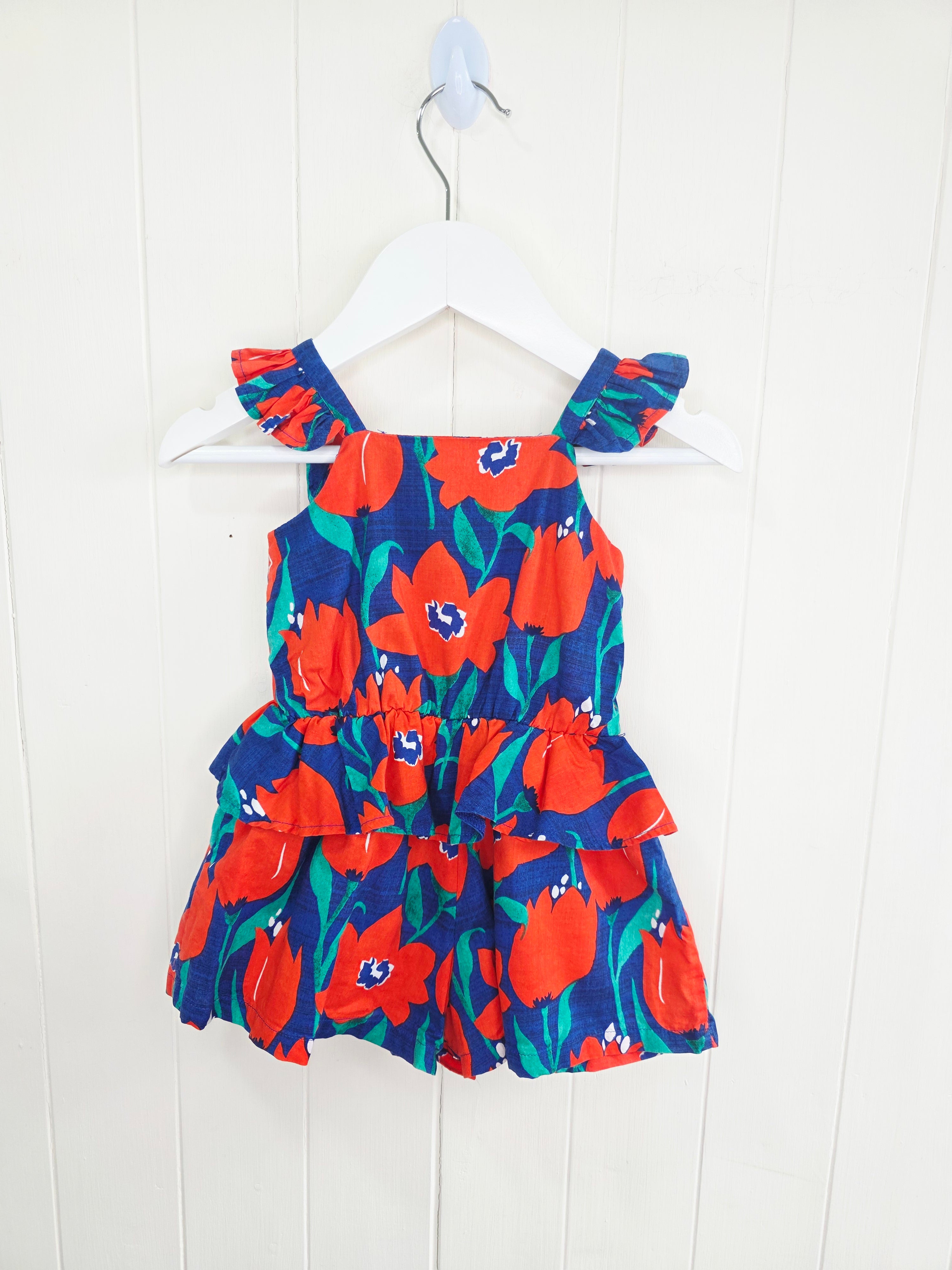 Next 3-6 months floral-print baby romper features a vibrant red and blue color scheme with ruffled straps