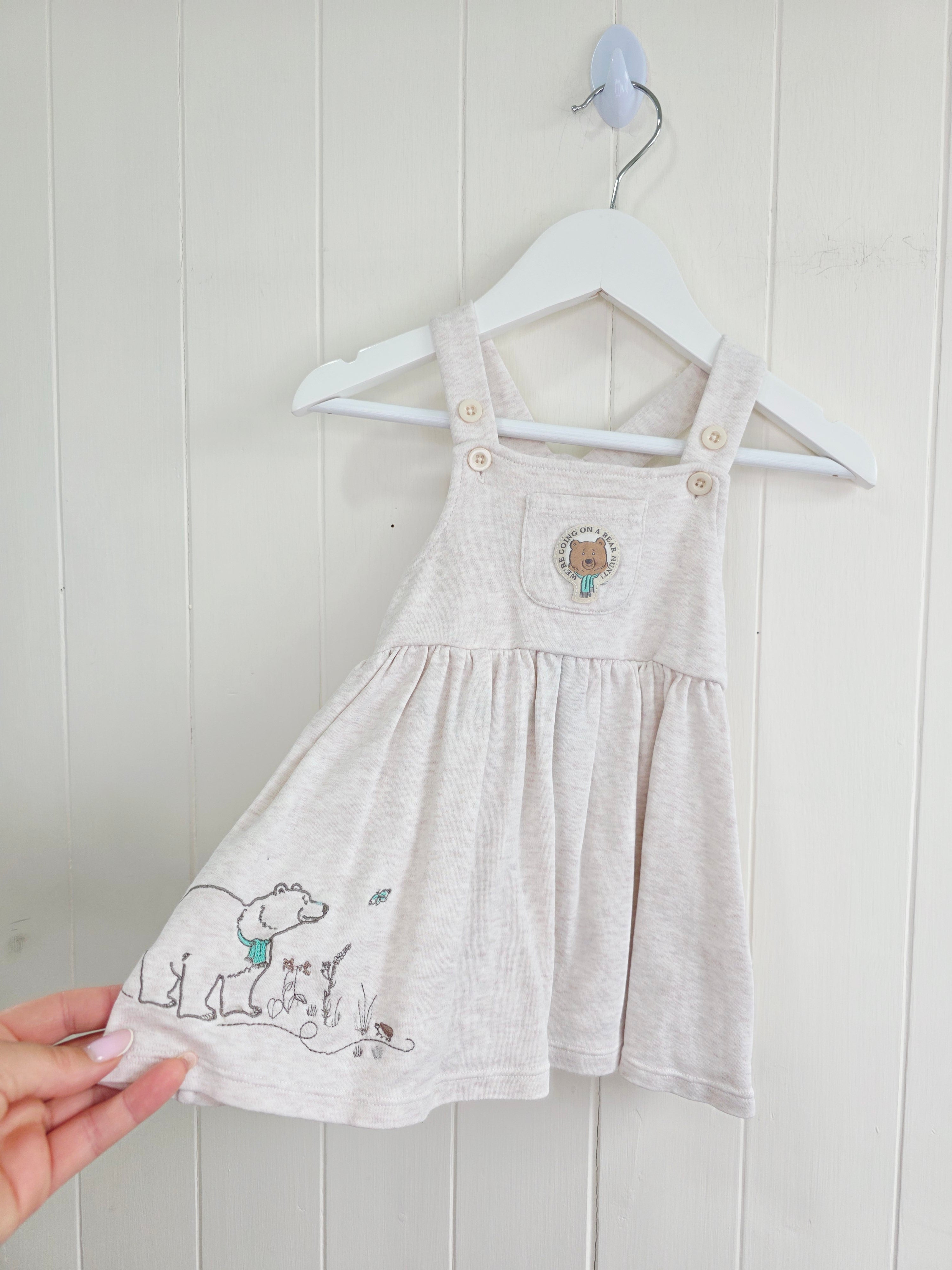 3-3 months pinafore dress features an embroidered "We're Going on a Bear Hunt" design and charming button details